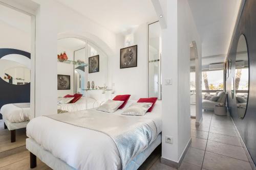 - une chambre blanche avec un grand lit et des oreillers rouges dans l'établissement Village Naturiste R4N - Le What Else Port Nature, au Cap d'Agde
