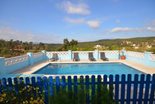 a swimming pool with chairs and a blue fence at Club Villamar - Apartment Amity in Maçanet de la Selva