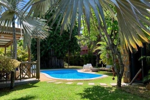 a swimming pool in a yard with a palm tree at Villa Banian Île Maurice in Bain Boeuf