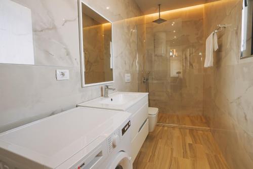 a white bathroom with a sink and a shower at JD Luxury Apartments in Vlorë