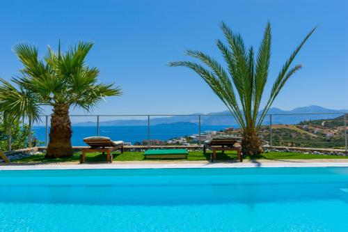 a pool with two benches and a view of the ocean at Villa Calypso Elounda in Elounda