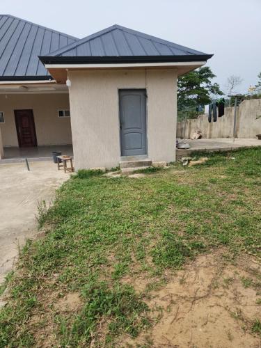 una piccola casa con una porta blu in un cortile di 3 Bedroom Serene home In Kwahu 