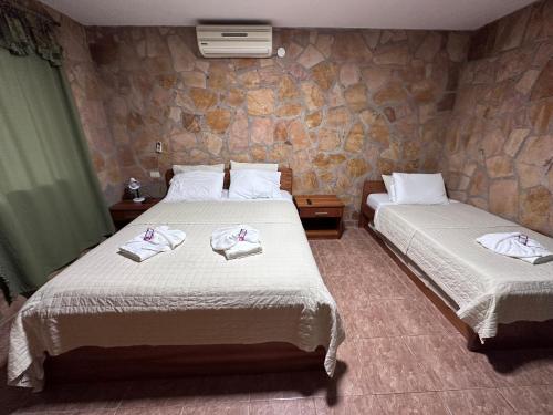 two beds in a room with a stone wall at Parque Hotel Manantial in Hohenau