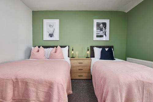 two beds in a room with green walls at Stunning House wParking Sleeps7 in Darlington