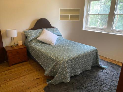 a bedroom with a bed with a comforter and a window at Gracious 1930s Art Deco House in Gosford