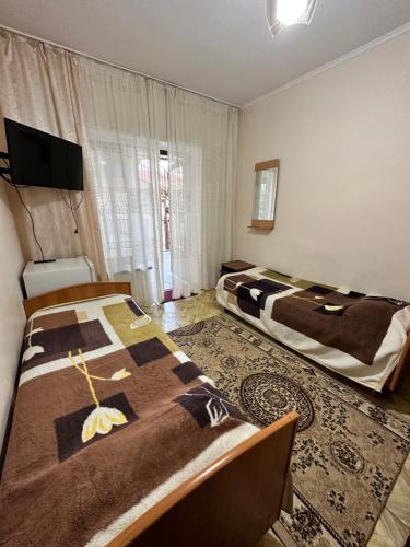 a bedroom with two beds and a flat screen tv at Гостевой дом "Kalinka" in Cholpon-Ata