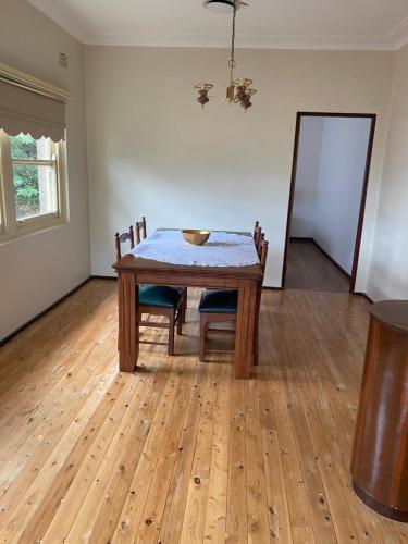 a dining room with a wooden table and chairs at Gracious 1930s Art Deco House in Gosford