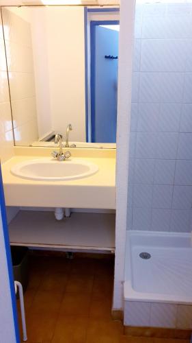 La salle de bains est pourvue d'un lavabo avec miroir et d'une porte bleue. dans l'établissement BAIE DES ANGES I Agréable 2 pièces cabine résidence avec piscine vue lagon Richelieu Cap d'Agde, au Cap d'Agde