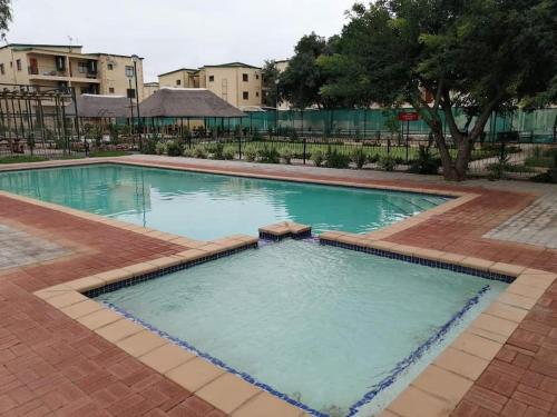 a large swimming pool with blue water at Ribbon 210's Two bedroom apartment in Gaborone