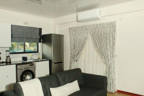 a living room with a black couch and a kitchen at Ribbon 210's Two bedroom apartment in Gaborone