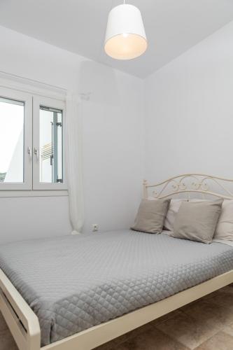 a white bedroom with a bed and a window at Kalliston Naxos in Akrotiri