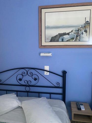 a blue bedroom with a bed and a picture on the wall at Stella Nomikou Apartments in Firostefani