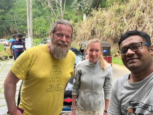 two men and a woman standing in front of a car at TK Homes in Badulla