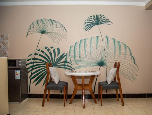 een tafel en twee stoelen met palmbladeren aan een muur bij Modern Furnished Rooms with Netflix, Kitchen, Living room , Laundry DStv and Free WiFi in Kampala