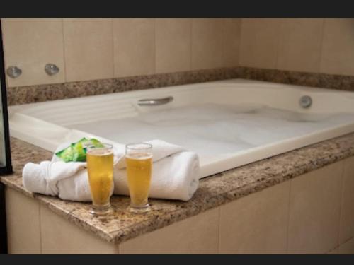 two glasses of beer sitting on a bath tub at Pousada Finlândia in Penedo