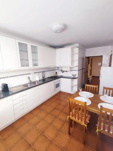 a kitchen with white cabinets and a table and chairs at Pertinho do Rio in Ponte de Lima