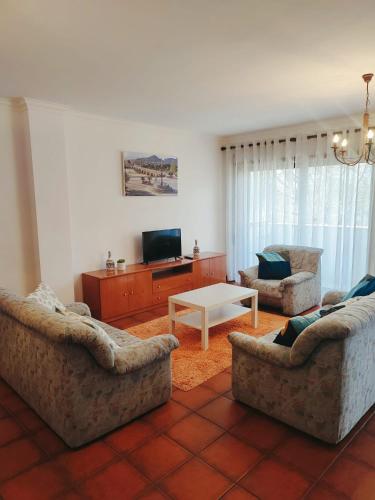 a living room with two couches and a table at Pertinho do Rio in Ponte de Lima