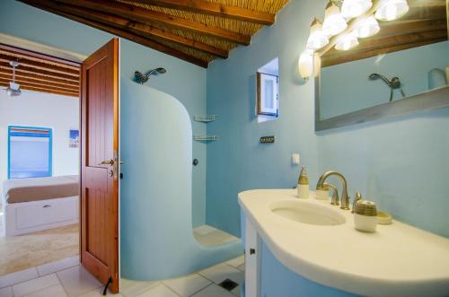 a bathroom with a sink and a mirror and a shower at IosVilla at Sapounohoma in Mylopotas