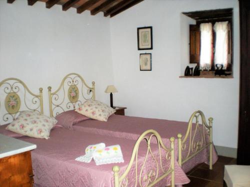 1 dormitorio con cama rosa y colcha rosa en Farmhouse in Cortona wit garden and pool, en Cortona