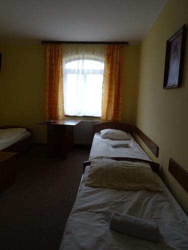 two beds in a room with a window at Hostel Miłosz in Grabowiec