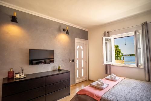 a bedroom with a bed and a tv and a window at Apartments Klara in Molunat