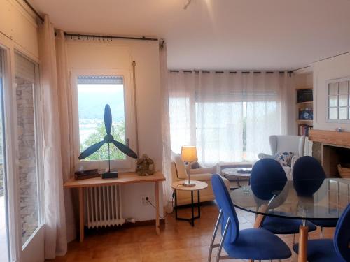 ein Wohnzimmer mit einem Glastisch und blauen Stühlen in der Unterkunft Tramuntana, casa amb bones vistes a mar, T in Port de la Selva