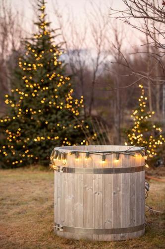a christmas tree in front of a wooden barrel with lights at Paradise near Reykjavik w. Sauna - Northern Lights in Mosfellsbær
