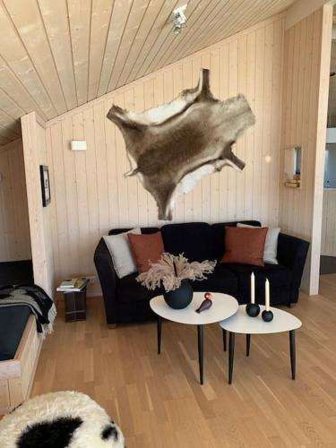 a living room with a black couch and two tables at Paradise near Reykjavik w. Sauna - Northern Lights in Mosfellsbær