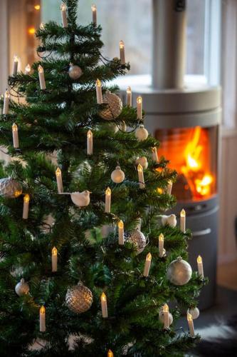 a christmas tree with candles on it next to a fireplace at Paradise near Reykjavik w. Sauna - Northern Lights in Mosfellsbær