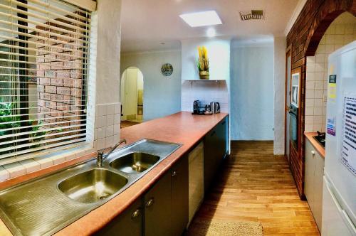 eine Küche mit einer Spüle aus Edelstahl und einer Theke in der Unterkunft Beach front 4 x2 Home with pool in Geraldton