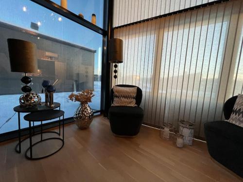 a living room with a chair and a large window at Attraktiv & smart funkishytte på Nes Strandhager. in Årnes