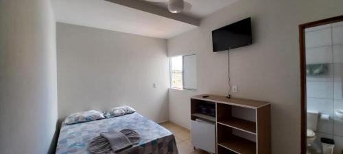 a small bedroom with a bed and a television at Pousada Nascer da Lua in São Thomé das Letras
