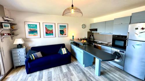 Il comprend une cuisine avec un canapé bleu et un réfrigérateur. dans l'établissement Appartement ou Studio la mer & la plage à vos pieds CALVI, à Calvi