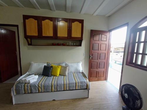 a bedroom with a bed with yellow pillows and a door at LAGOA I - Saquarema RJ in Saquarema