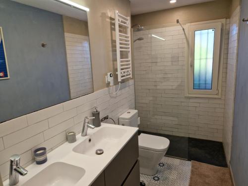 bagno con lavandino, servizi igienici e specchio di Villa Casa Cis a Calella de Palafrugell