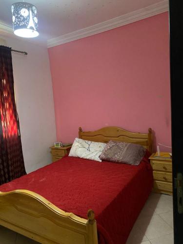 Schlafzimmer mit einem Holzbett mit einer roten Tagesdecke in der Unterkunft Hill sight cozy in Tangier