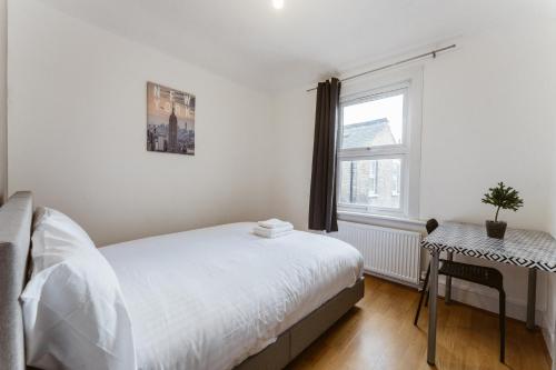 a white bedroom with a bed and a window at Mile end Double rooms 86a in London