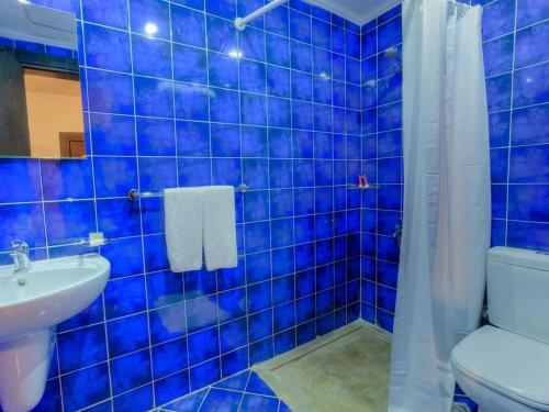 Baño de azulejos azules con aseo y lavamanos en Porto matrouh chalets, en Marsa Matruh