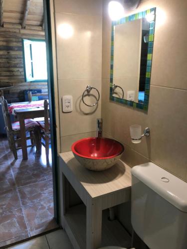 a bathroom with a red sink and a toilet at Cabañas del Mesón in Potrerillos