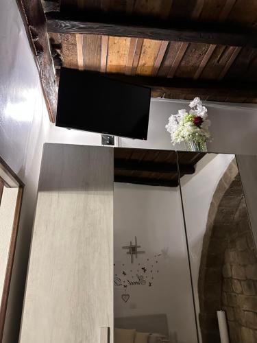 a room with a tv and flowers on a mirror at Casa medievale Il Rifugio di Olimpia in Viterbo