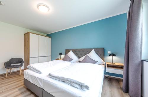 a bedroom with a large white bed with a blue wall at Ferienwohnungen am Wasser - Krakow am See in Krakow am See