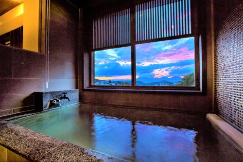 a bath tub with a window in a bathroom with a view at Sakaeya in Yamanouchi
