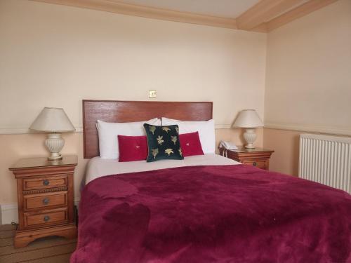 um quarto com uma cama grande e almofadas vermelhas em The Royal Oak Hotel em Ramsgate