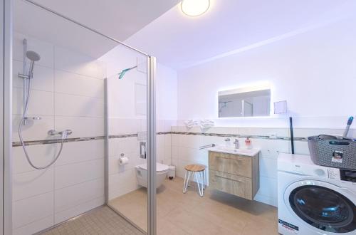 uma casa de banho com um chuveiro e uma máquina de lavar roupa em Ferienwohnungen am Wasser - Krakow am See em Krakow am See
