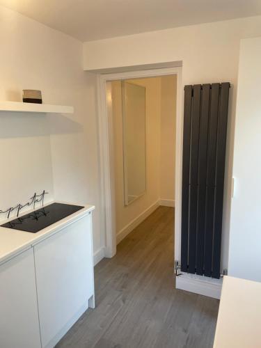 a kitchen with white cabinets and a black radiator at Lux Cottage Conwy in Conwy