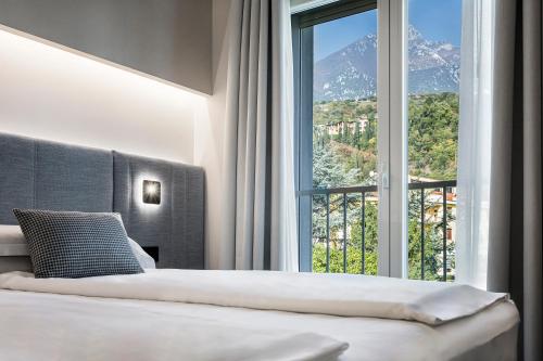 a bedroom with a bed and a large window at Reflection Boutique Hotels in Toscolano Maderno