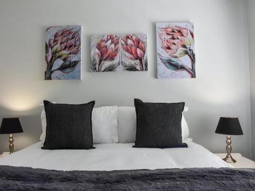 a bedroom with four paintings on the wall above a bed at De Hoek Selfsorg Eenhede in Beaufort West
