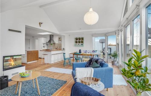 a living room with a blue couch and a kitchen at Nice Home In Kirke Hyllinge in Kirke-Hyllinge