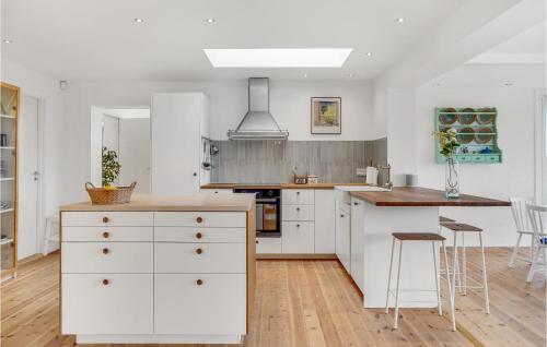 a kitchen with white cabinets and a wooden floor at Nice Home In Kirke Hyllinge in Kirke-Hyllinge