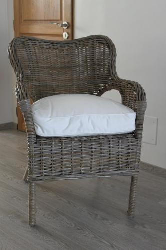 a wicker chair with a white pillow on it at L'Ansolanette - Chambre d'hôtes in Fuveau